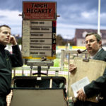 2 men stand at the betting sign at the greyhound races stadium