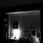 Older woman sits on bed
