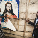 Woman and man pray with Jesus banner on the wall