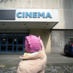 Girl points with her finger at the cinema building