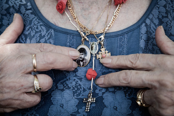 An elderly woman shows her gold jewelry on her chest