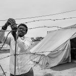 Refugee secures the fence around his tent, Choucha refugee camp