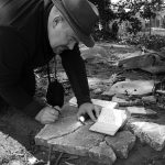 Marek Łuczak PhD is documenting on his knees recovered tombstones