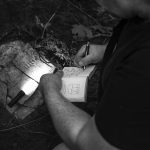 Dr Marek Łuczak documents in his writing pad the recovered tombstone illuminated with the electric torch